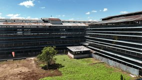 An aerial view showing a large abandoned rubber factory with a rusted corrugated metal roof and multi-story industrial structures in Indonesia. - Powered by Shutterstock - Get 15% off with code: PIKWIZARD15