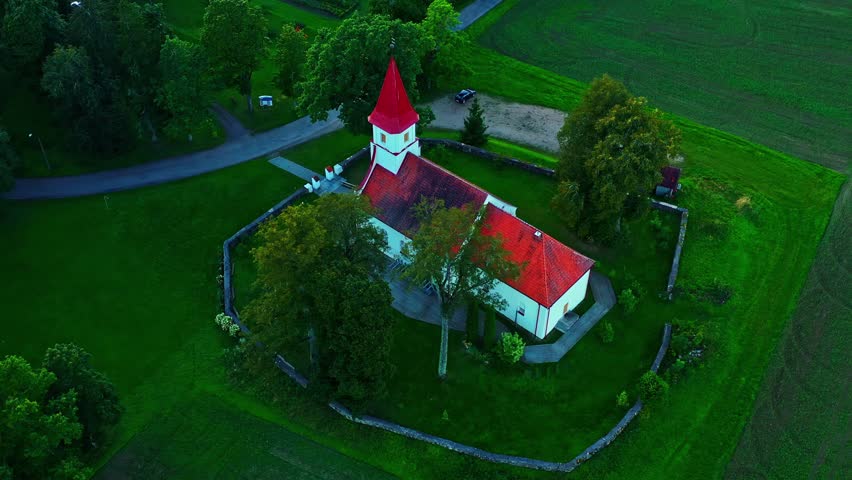 Charming rural chapel surrounded by trees and agricultural fields in aerial view