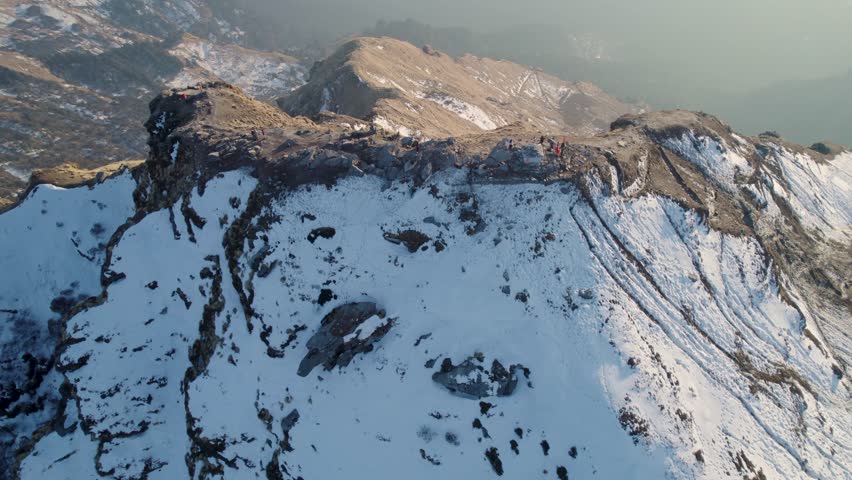Aerial view of Tungnath temple area on a snow-covered mountain ridge with rocky peaks and misty valleys Rudraprayag, Uttarakhand, India.