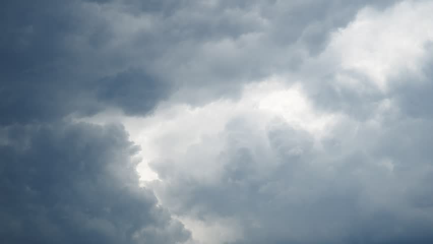 Gray clouds fill the sky as they gather thickly. The storm approaches steadily with a strong wind. The light fades as the weather turns dark and heavy.