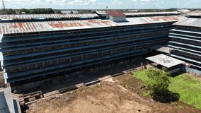 An aerial view showing a large abandoned rubber factory with a rusted corrugated metal roof and multi-story industrial structures in Indonesia. - Powered by Shutterstock - Get 15% off with code: PIKWIZARD15