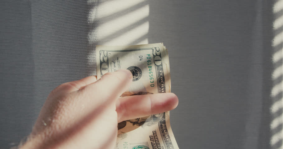 Close-up of man hands counting money 20 dollar bills.
