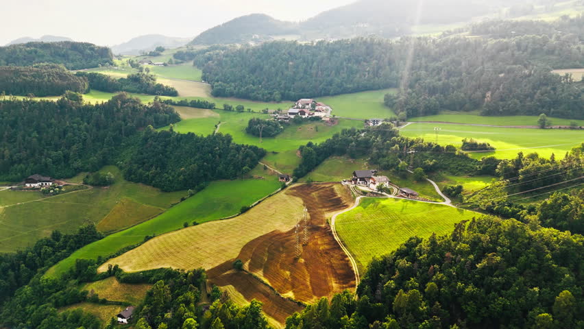 Alpine countryside with cultivated land and farmhouses in Dolomites, South Tyrol, Italy, aerial view of mountain valley landscape