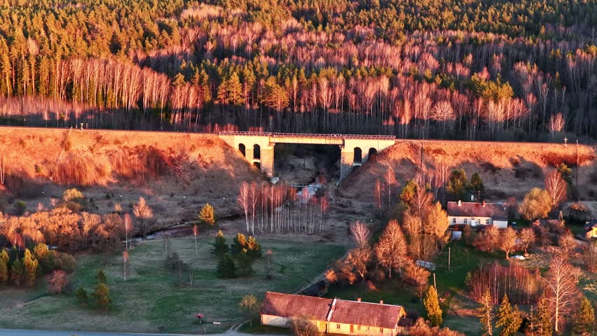 Aerial view of a railway bridge and a flowing river at beautiful golden hour sunset