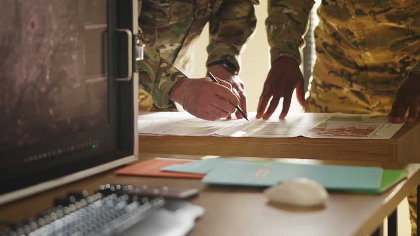 Two military officers using topographic map to develop offensive strategy