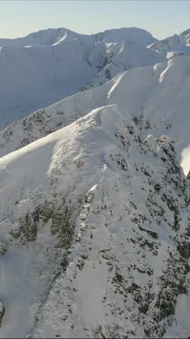Vertical view looking down at a beautiful snow-covered mountain slope and alpine valley in winter.