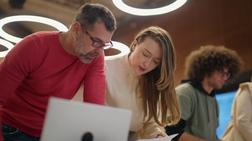 A group of coworkers works together on a project in a contemporary office setting. Employees actively engage in collaborative tasks and discussions.