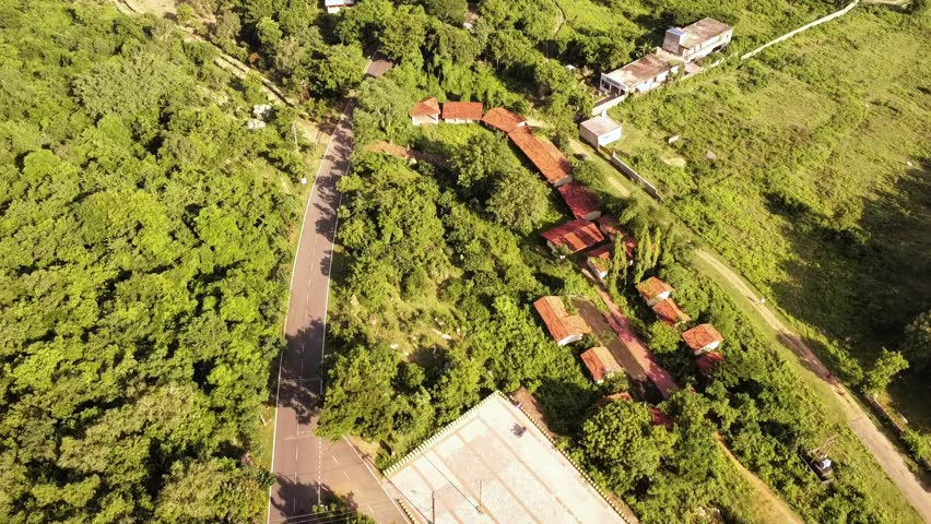Aerial View of Indian Rural Village Houses with Red Roofs in Lush Green Jungle. Overhead Shot of Rural Houses Surrounded by Dense Green Trees and Nature.
