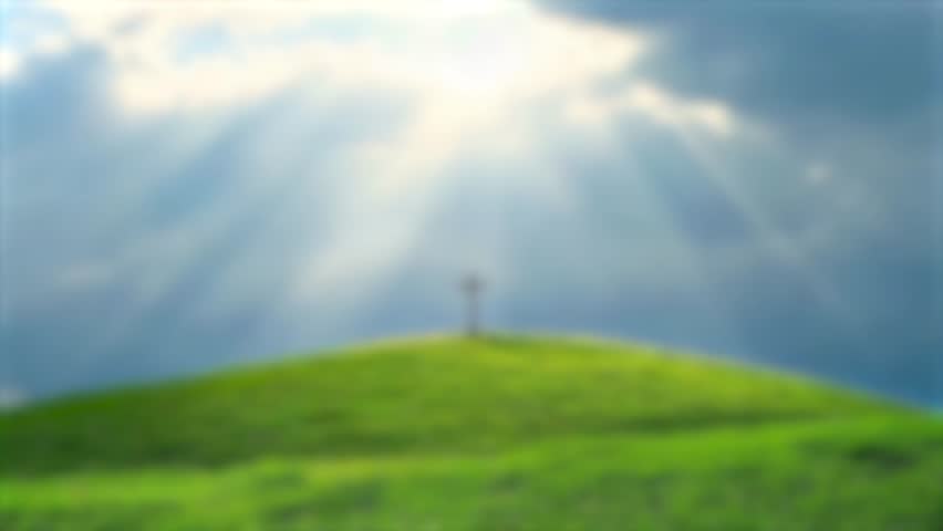 Cristian cross on top of a green hill at sunset on with blur background