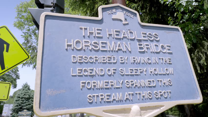 Close up view of the blue New York state historical marker sign for The Headless Horseman Bridge. The sign commemorates Washington Irving