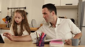 A father helps his daughter with homework or studying at a kitchen table, using a tablet and surrounded by books and colored pencils. - Powered by Shutterstock - Get 15% off with code: PIKWIZARD15