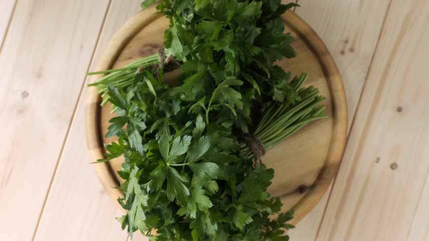 Fresh organic green parsley bunches spinning on a round wooden cutting board