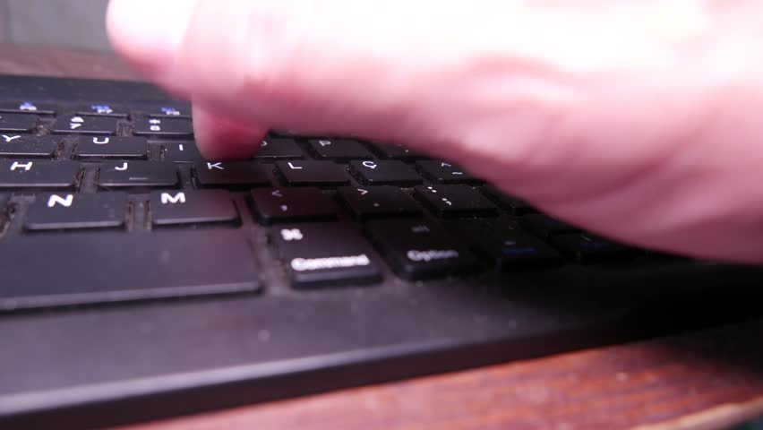 POV of a man typing on a dirty computer keyboard. A dusty keyboard on the table. A wireless keyboard (QWERTY). A dirty keyboard, close-up. Typing with one hand. Writing on the computer. Dust.