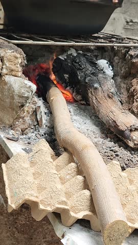 Jacaranda and mezquite firewood logs burning inside a traditional outdoor campfire