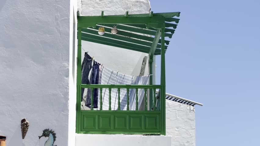 Traditional green wooden balcony with hanging laundry on a white facade in a village in Lanzarote, Canary Islands, Spain