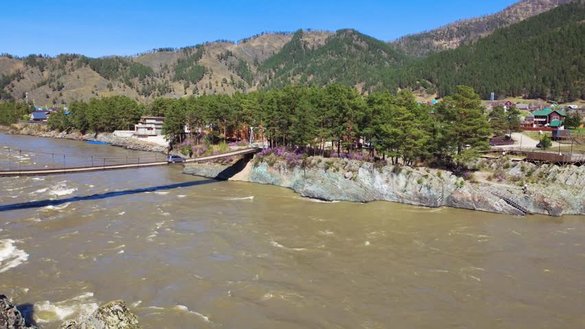 River Crossing Bridge. Aerial Footbridge Stretching Across Floodwaters Next To Pinelined Coast. Suspended Bridge Spanning Over River With Pine Trees Nearby And Elevated Walkway Along Shoreline