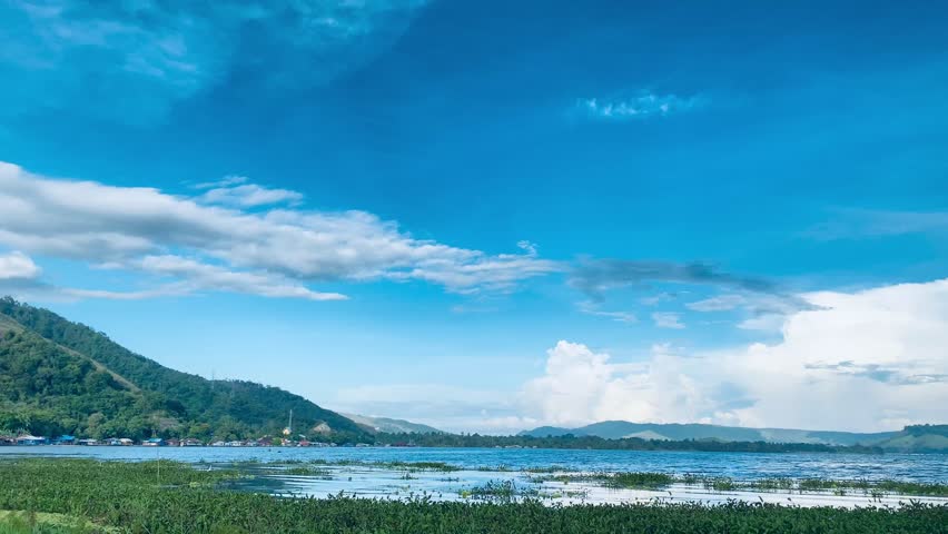 Calm Lake Landscape With Wetlands, Blue Sky and Puffy Clouds Over Distant Hills