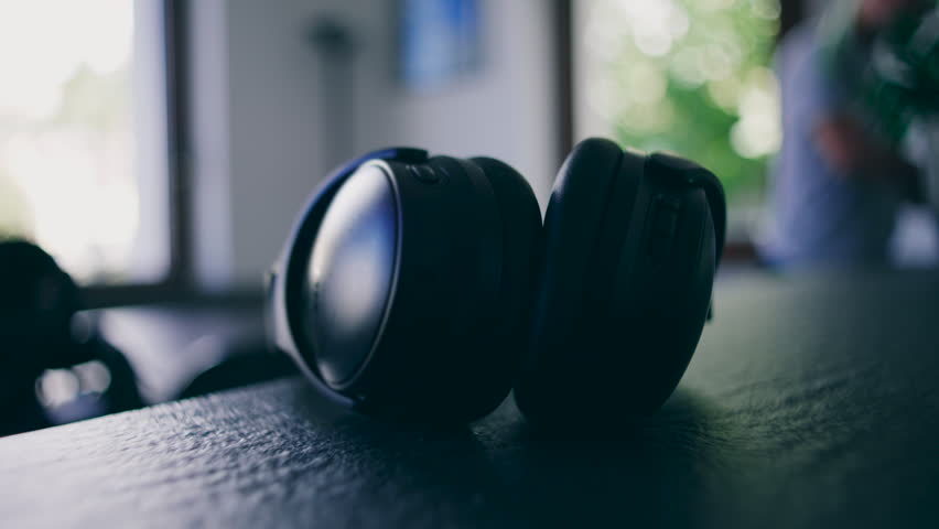 A pair of headphones sits on a table in soft indoor light, highlighting the simple presence of everyday technology within a peaceful home environment