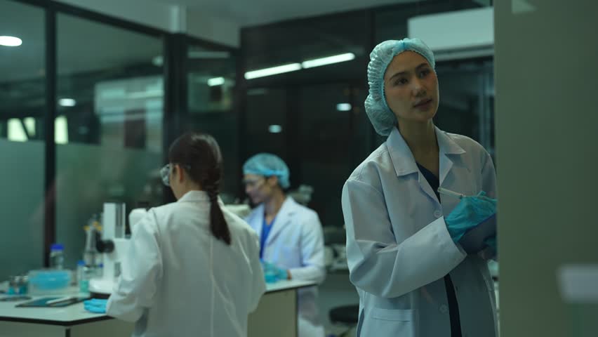 Life scientists researching in laboratory. Focused female life science professional pipetting solution into the glass cuvette. Healthcare and biotechnology concept.