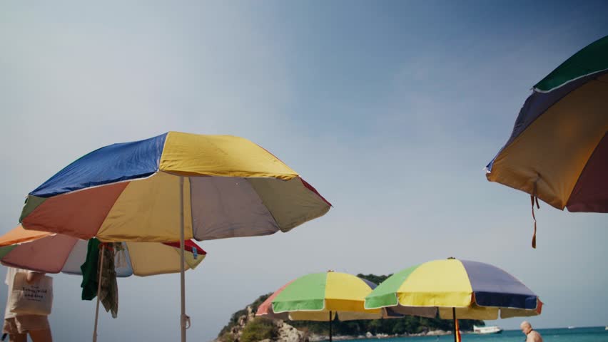 Woman walking on a beach with colorful umbrellas