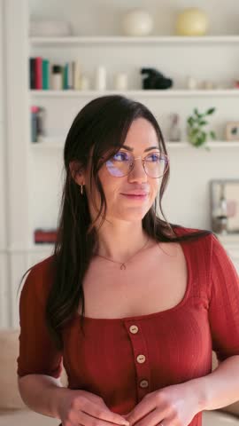 A Happy Woman with Glasses Smiles Brightly at the Camera in a Cozy Home Setting