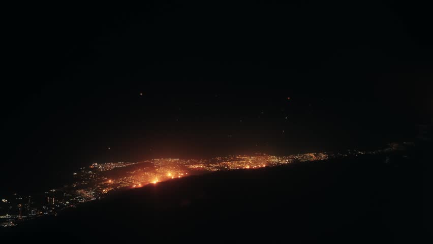 Aerial view from plane flight of city in Kuwait with glowing oil plant fires and lights at night