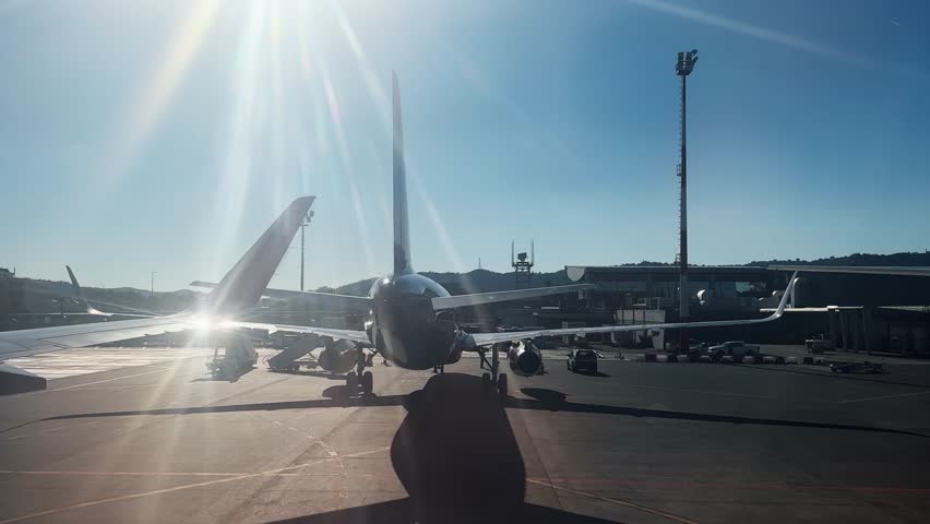 Arrival pov with airplane parked tarmac under bright sunlight during early morning at Mother Teresa airport in Tirana, Albania