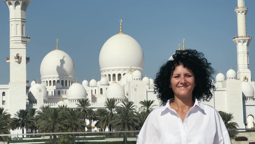 Smiling tourist woman sightseeing Sheikh Zayed Grand Mosque in Abu Dhabi, UAE