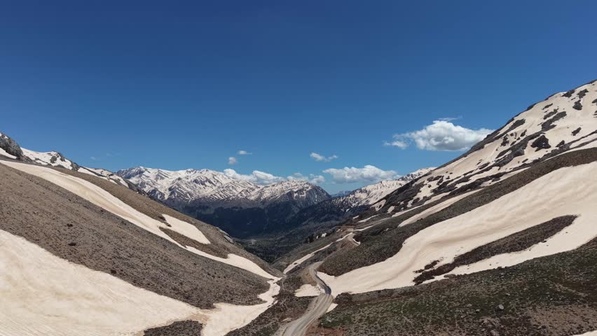 Snowy mountain landscape. on top of the mountain. Snow-covered mountain road, high snowdrifts on the sides. High quality 4k footage