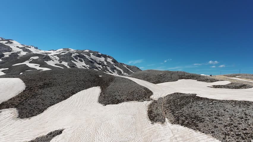 Snowy mountain landscape. on top of the mountain. Snow-covered mountain road, high snowdrifts on the sides. High quality 4k footage