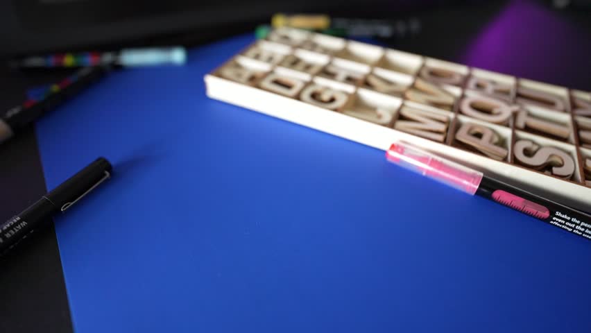 Close-up of a person placing a wooden letter W on a blue background