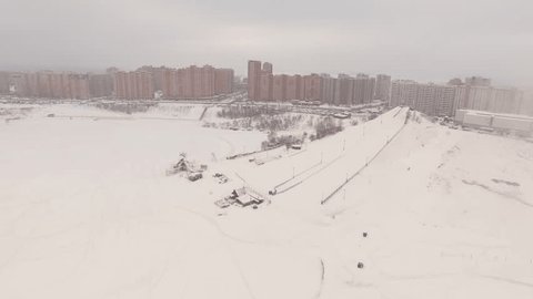 Aerial Drone Flight Over Ski Slope Towards City in Winter