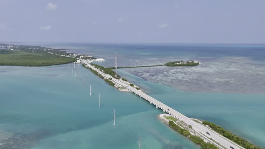 Aerial view of turquoise ocean, mangrove island and Overseas Highway in Florida Keys with boats and clear water. g.