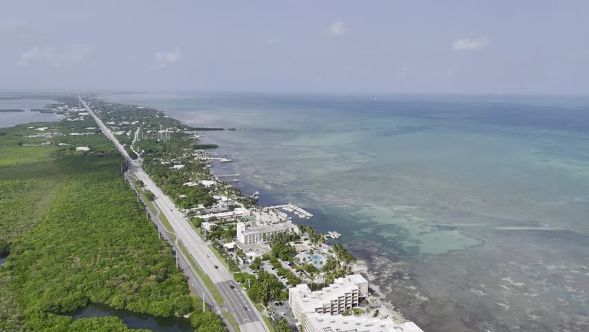 Aerial view of turquoise ocean, mangrove island and Overseas Highway in Florida Keys with boats and clear water. g.