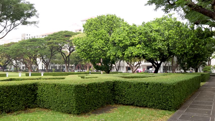 A slow panning shot reveals manicured hedges, green trees, and a fountain on campus
