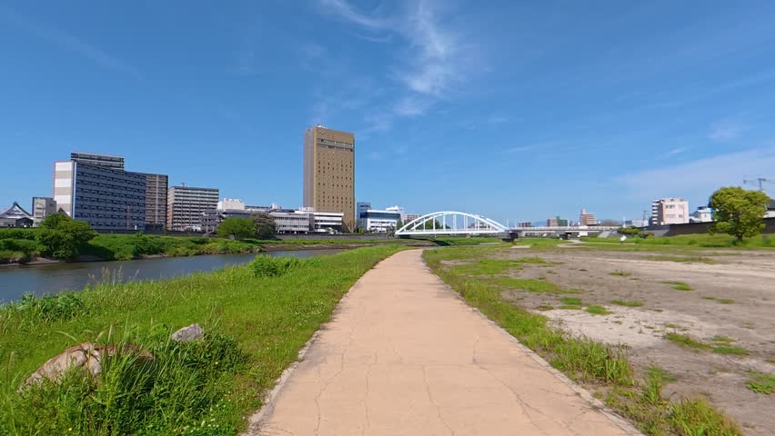 POV shot of moving forward along a scenic riverside path under a blue sky