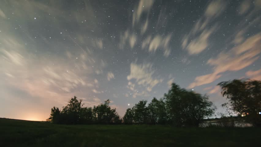 A timelapse of the starry sky over a lake on a summer night