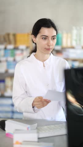  Young female pharmacist working with computer in pharmacy