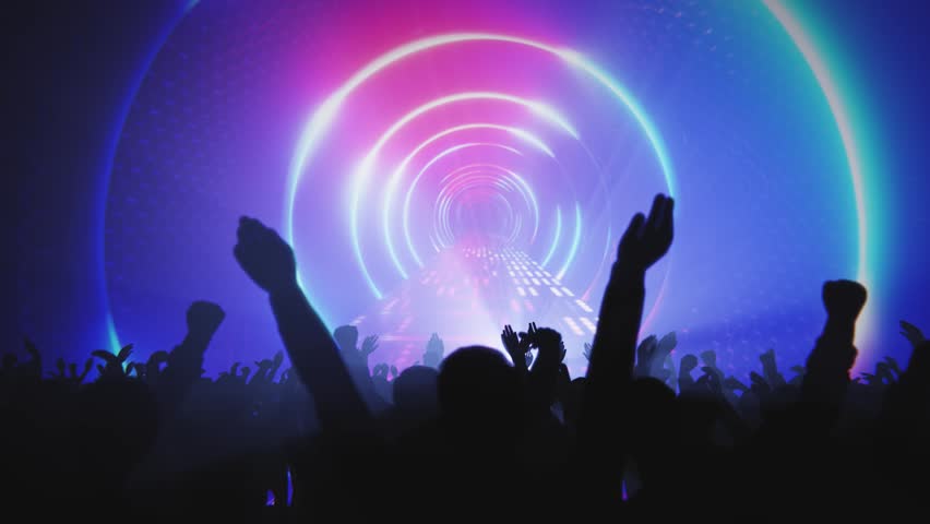 Concert crowd with raised hands enjoying the music and vibrant light show.