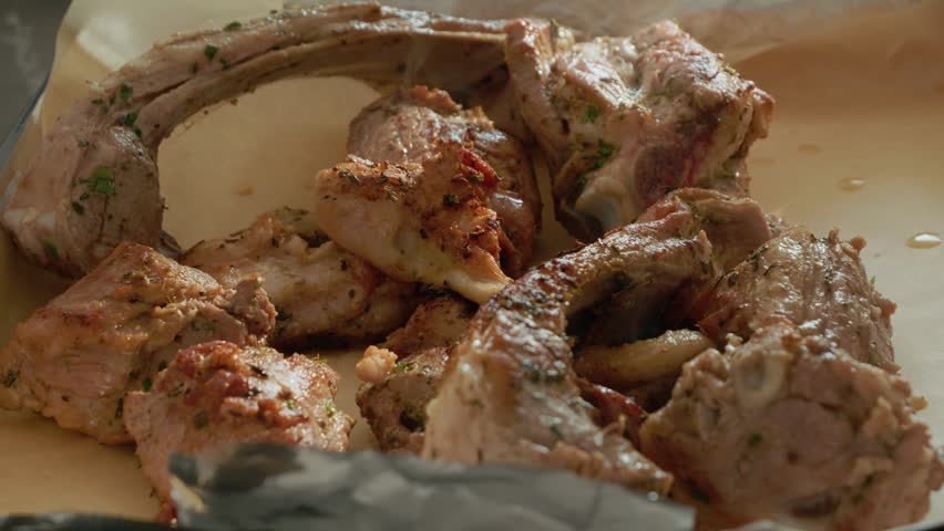 Lamb meat is arranged on a tray in the kitchen, ready to be placed in the oven for cooking. The smell of the lamb fills the air as it starts to cook.