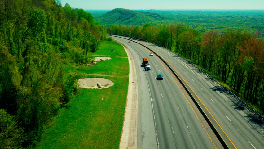 Step deck semi-truck hauling huge yellow construction machinery on I-26 in Appalachian North Carolina.