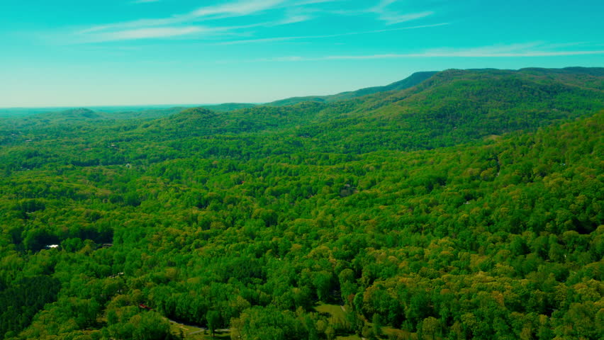 Blue Ridge Appalachian foothills in western North Carolina near Tryon, with lush spring forest canopy, layered ridges fading into atmospheric blue haze.