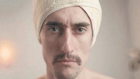 Comical mustached man in bathroom with towel on head staring intently, handsome funny guy, serious thoughtful look - Powered by Shutterstock - Get 15% off with code: PIKWIZARD15
