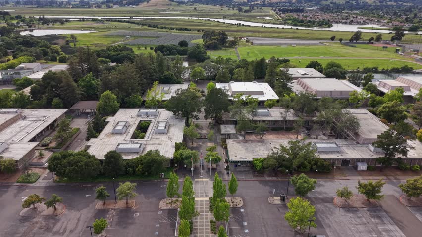Aerial footage of Napa Valley College in California, revealing the campus architecture, parking lots, green spaces, and the surrounding lush landscape with the Napa river in the background