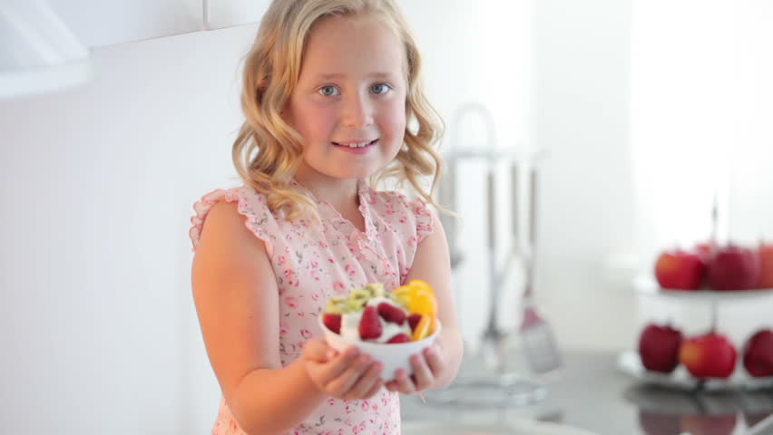 Girl holding a plate of fruit yoghurt
