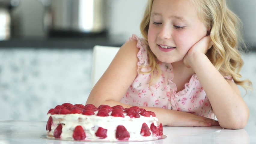 Girl looking at big cake and smiling
