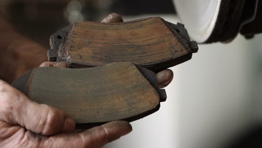 Close-up of two old car brake pads in a man