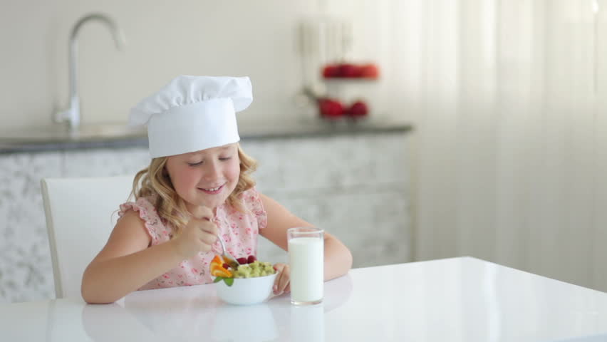 Child sitting at table and eating fruit yogurt
