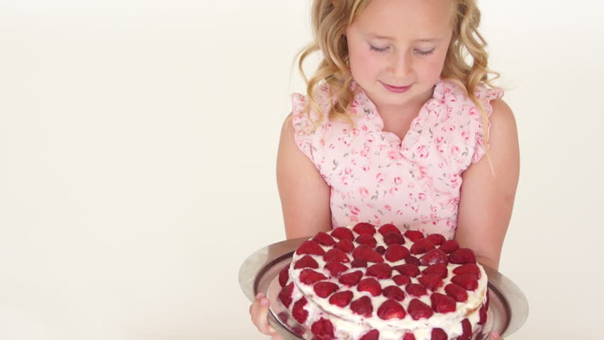 Girl holding strawberry cake and looking at camera with smile

