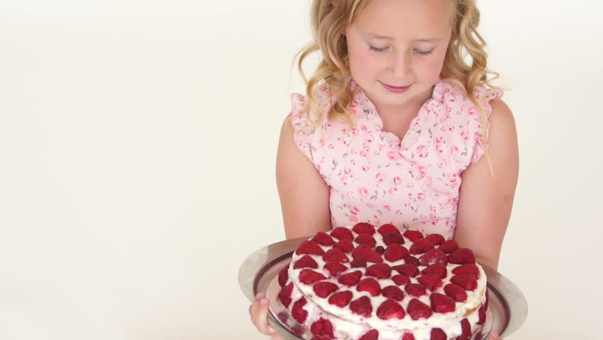Girl holding strawberry cake and looking at camera with smile

